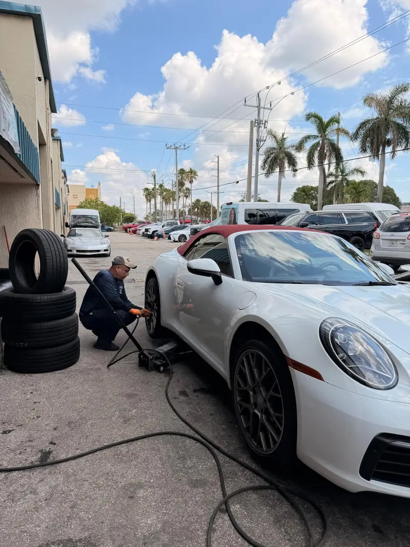 Tech changing a front tire on a Porsche 911 at the shop